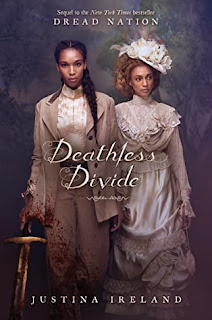Two Black women in fancy cream and white clothing, the one on the left is holding a sword in her right hand, her sleeve and pant-legs are splattered with blood.