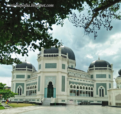  Masjid Raya AL- Mashun Medan Tempat wisata Religi yang kini berusia 113  Tahun  Medan seperti tak ada habisnya untuk ditelusuri, kamu yang suka wisata sejarah atau heritage seperti Saya pasti tak akan melewatkan tempat yang satu ini, yah Masjid Raya Al- Mashun Medan meninggalkan banyak sejarah di dalamnya. Masjid yang berlokasi tak jauh dari pusat kota Medan ini terletak di Jalan Sisingamangaraja No.61Medan Maimun. Pembangunan Masjid Al- Mashun sendiri dimulai pada tanggal 21 Agustus 1906 (1 Rajab 1324 H) oleh Sultan Ma’mun Al- Rasyid Perkasa Alam yakni pemimpin Kesultanan Deli pada masa itu. Dan secara keseluruhan pembangunan selesai pada tanggal 10 september 1909 yang artinya waktu pembangunan yang dibutuhkan adalah 3 tahun lebih. Dilansir dari Simas.kemenag.go.id Masjid yang Luas bangunannya sampai 5.000 m2 menelan biaya pembangunan mencapai satu juta Gulden. Kemudian Masjid ini juga ini memiliki daya tampung hingga 1.500 jamaah. Masjid yang dibangun di atas lahan seluas 18.000 kini sudah memasuki usia satu abad lebih, tepatnya berumur113 Tahun.  Menurut sejarahnya, Sultan Ma’mun Al-Rasyid memang sengaja membangun Masjid ini dengan megah, karena menurut prinsip nya hal itu lebih utama ketimbang kemegahan Istananya sendiri, yakni Istana Maimun yang berjarak 200m dari Masjid. Kemudian, pembangunan Masjid ini ditanggung sendiri oleh Sultan Ma’mun Al- Rasyid, namun konon katanya Tjong A Fie, tokoh saudagar kaya dari etnis Tionghoa ini pun turut berkontribusi dalam pendanaan pembangunan Masjid Raya ini. Pada mulanya arsitek yang merancang bangunan Masjid Raya ini merupakan Van Erp arsitek asal Belanda yang sebelumnya juga merancang Istana Maimun, namun kemudian prosesnya dikerjakan oleh JA Tingdeman. Alasanya karena ketika itu Van Erp dipanggil ke pulau Jawa oleh pemerintah Hindia Belanda untuk bergabung dalam proses restorasi candi Borobudur di Jawa Tengah. Kemudian JA Tingdeman merancang masjid ini dengan denah simetris segi delapan dalam corak bangunan campuran Maroko, Eropa dan Melayu serta Timur Tengah.  Pada bangunan masjid dibagi atas beberapa ruang utama, tempat wudhu, gerbang masuk dan menara. Ruang utama, tempat sholat berbentuk segi delapan tidak sama sisi. Pada sisi berhadapan lebih kecil, terdapat beranda yakni serambi kecil yang menempek menjorok keluar. Di bagian dalam masjid terdapat pilar utama berdiameter 0.60 m yang menjulang tinggi. Masjid Raya Al- Mashun didominasi warna putih, di samping hijau pada sekitar bagian pintu-pintu dan warna hitam pada kubahnya. Pilar-pilar yang terdapat pada setiap sisi bangunan untama mengambil corak khas Cordoba dan spanyol, terutama dengan lekung bagian atas yang berbentuk setengah lingkaran. Untuk membangun Masjid Raya Al- Mashun banyak dekorasi yang diimpor dari mancanegara seperti marmer dari Italia, kaca patri asal Cina, dan lampu gantung dari Prancis. Seriap ornamen dihiasi dengan ukiran-ukiran indah bermatif floral atau geometris. Keindahan Masjid Raya Al-Mashun dan Istana Maimun menandakan tingginya peradaban Kesultanan Deli, sebagai suatu kedaulatan etnis Melayu yang sempat berjaya pada zaman lampau. 