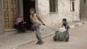 Niño palestino empuja un contenedor de agua.