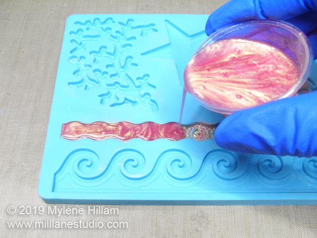 Pouring resin into the long wavy shape of the silicone mould.