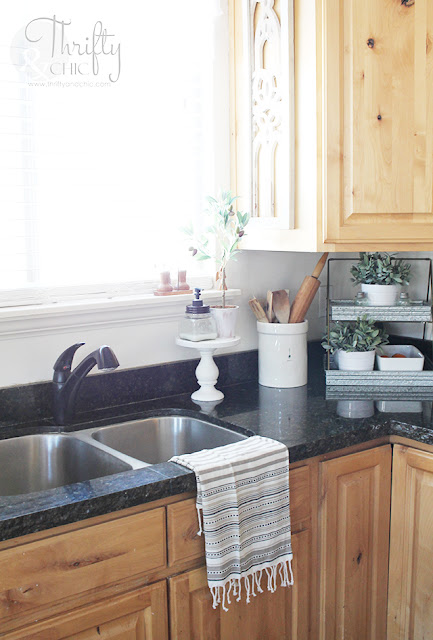 kitchen with knotty alder cabinets, white board and batten island, and black granite counter tops with an unfinished edge.