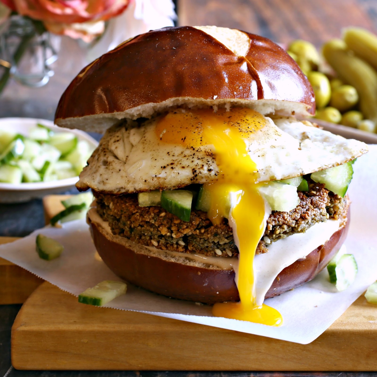 Breakfast sandwich with a falafel patty, tahini, diced cucumbers and topped with a fried egg.