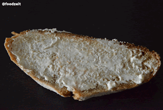 Fresh cut slice of bread with cream cheese topping