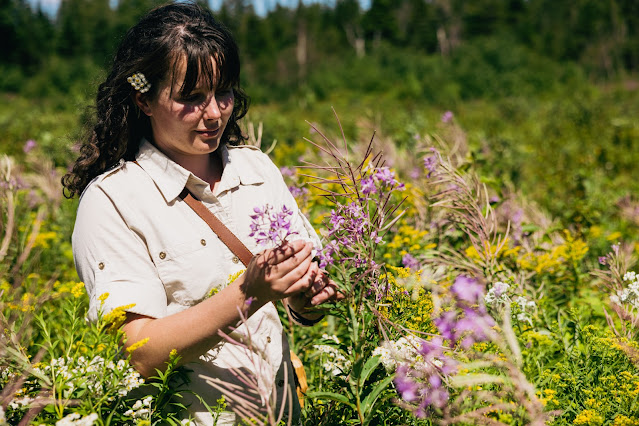 A woman standing in a field gathering wild flowers