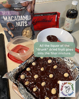 A pan of fudge rests on a kitchen counter surrounded by all the ingredients that went into it. A sticker on the photo encourages the reader to add all the liquor from the soaked dried fruit into the fudge mixture.