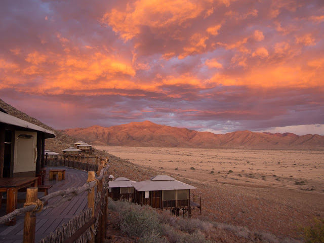  Namibia – vùng đất bị bỏ rơi, khắc nghiệt và cháy nắng, vùng đất chu du của mặt trời thách thức những giới hạn con người. Phủ đi những nét mờ nhạt của cấu trúc chưa hoàn thiện, Namibia tự “tô” thêm cho mình mảng màu lộng lẫy giữa sắc trắng của chân trời, màu xanh của mây hòa trong sắc đỏ ngã nâu của ánh mặt trời vừa ló mỗi sáng hay lụi tắt mỗi chiều. Cung đường của bạn sẽ tuyệt vời nhất vào bình minh và hoàng hôn. Thử ngừng bánh, leo lên nóc xe, thỏng chân mà ngắm nhìn mặt trời đang tràn ra, tráng hồng cả vùng trời rộng lớn.