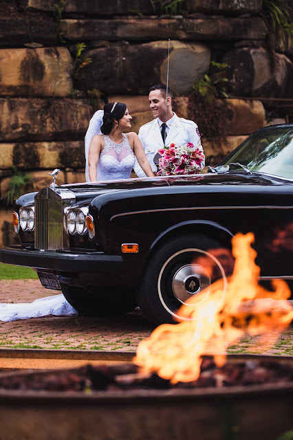 noivos atras do carro roll-royce e na frente a chama de um fogo