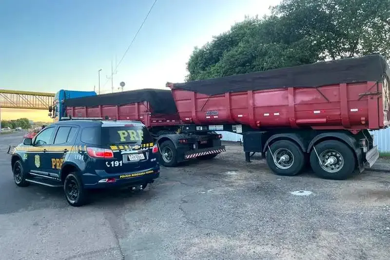 Viatura da PRF ao lado de bitrem basculante carregado de areia