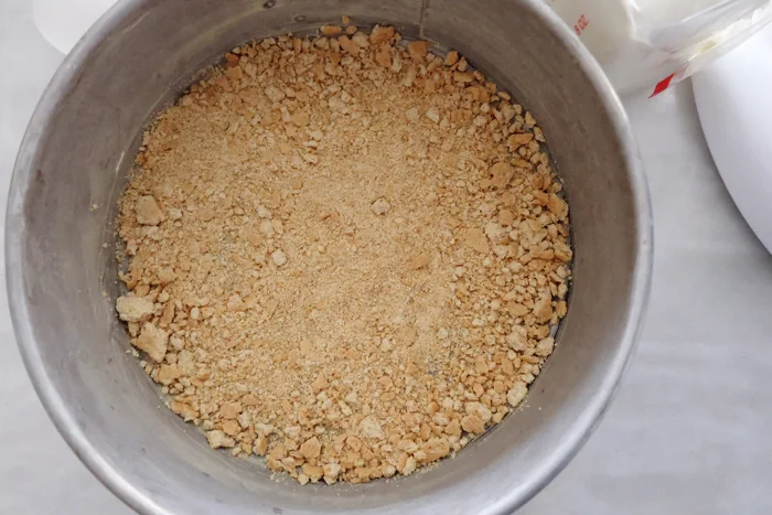 sprinkling graham cracker crumbs on bottom of pan