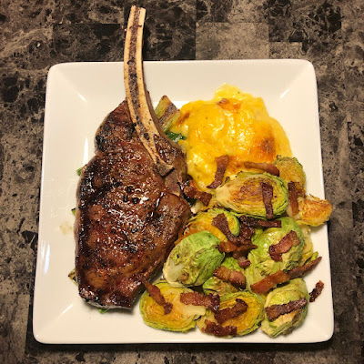 Rare grilled bone-in bison ribeye, maple bacon roasted Brussels sprouts and cheesy potato casserole