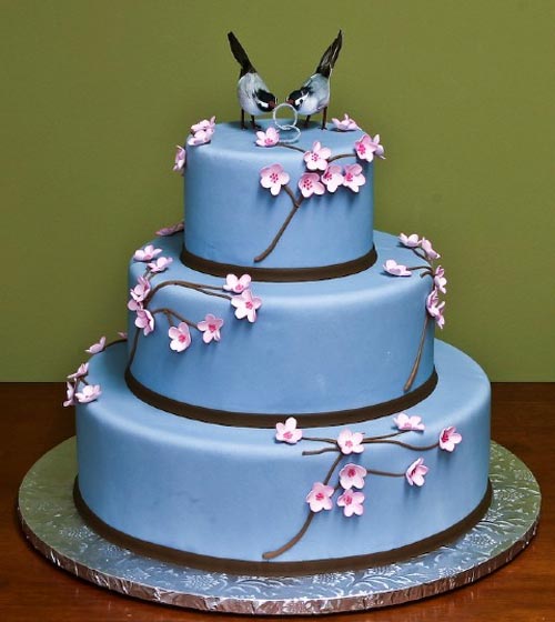 Three tier pastel blue wedding cake with delicate pink cherry blossoms and 