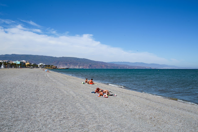 Playa de arena gruesa con las azules aguas del mar a su frente