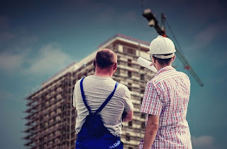 man points at skyscraper under construction by a system independent of him