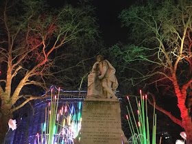 Pic of Shakespeare's statue surrounded by lit-up trees and plants of light