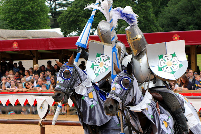 foto de recriação dso torneios medievais mostrando dois guerreiros montados a cavalo com suas armaduras fechadas, lanças e escudo com o símbolo da casa de York