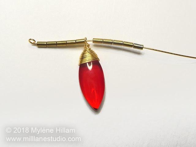 Length of wire strung with gold tube beads and red dagger drop.