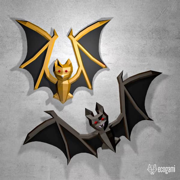 one silver and black and one gold and black low poly bat, each with red eyes, displayed on wall