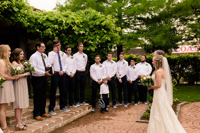 The bride and groom met in college, and have been together for three and a half years.  Maggie said that walking down the aisle towards Jordan was the best part of the day, knowing that they were surrounded by the love and support of friends and family.  She said, “As I walked towards him, Jordan and I were both tearing up and we couldn’t look away from each other.”  Jordan said that since he was “anxious all day, to the point of feeling sick,” the first look was the most memorable part of the day.  He said, “The moment I saw Maggie, I felt 100% relieved, and it made the hours before the ceremony so much more enjoyable.”    The Festivities Event Center in El Reno, OK, was the perfect wedding backdrop, with 10’ windows, a whole second floor to get ready in, and a romantic setting for the outdoor nuptial.  The bride looked “drop-dead gorgeous” in her lace-embroidered, strapless, wedding gown, followed by her bridesmaids, dressed in individually designed gowns in soft hues of dusty rose.  Each bridesmaid had a spring floral bouquet, similar to the bride’s bouquet of pastel pink roses and lilies.    After the couple exchanged wedding vows, pictures of the family and wedding party were taken, and it was time to celebrate!  First dances came next, then guests were invited to enjoy a Mexican buffet.  Dessert included the gorgeous wedding cake, chocolate groom’s cake, and assorted, homemade cookies and pastries.  The evening came to a close as the guests sent the star-gazed couple off with sparklers!  The newly married couple escaped to Cozumel and Yucatan Progreso for their honeymoon.  