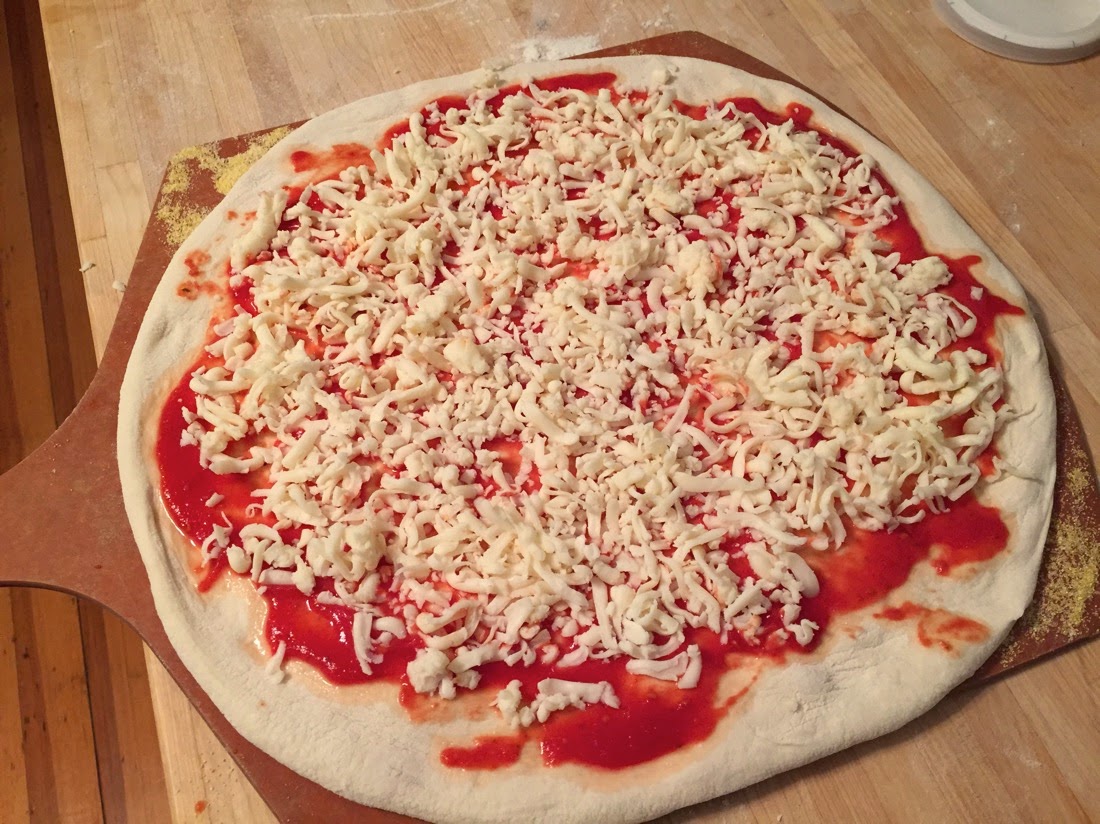 Image of pizza dough topped with sauce and cheese.