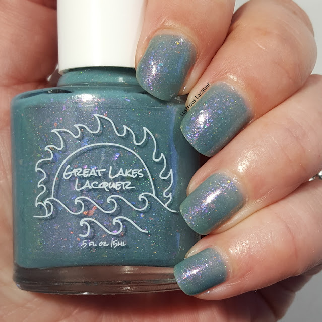 Blue-grey nail polish in a jelly finish with iridescent falkes and scattered holo glitter