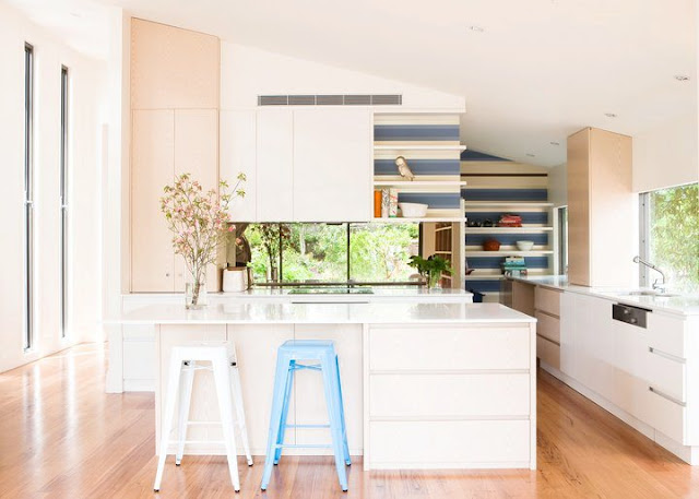 kitchen with blue and white backsplash, white island, wood floors and white counters and cabinets with a lot of natural light