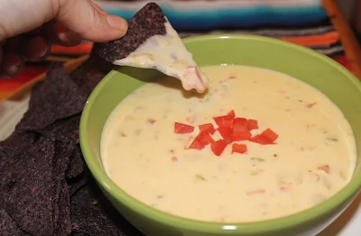 Chip dipping into a bowl of queso blanco dip.