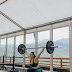 Woman holding black barbell beside windows