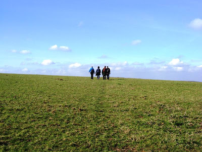 Four walkers on the distant horizon between grass and sky