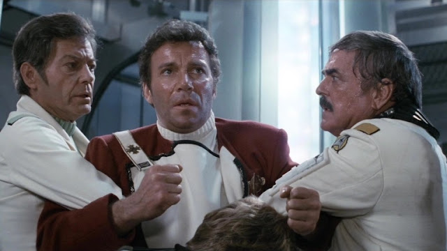 Dr. McCoy (DeForest Kelley) and Scotty (James Doohan) hold Kirk back from the radiation-filled engine room