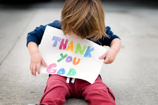 toddler holding a sign that says Thank you God