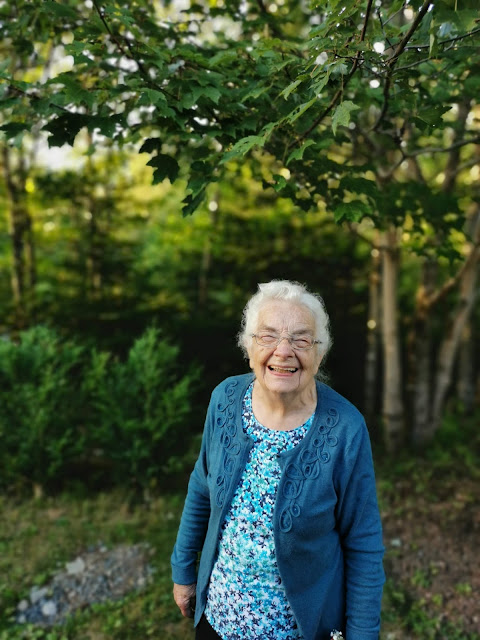 grandmother smiling outside surrounded by blurred trees