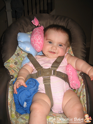 Baby in high chair with various props supporting her head and body