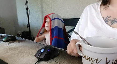 toddler sitting at computer with a blanket on his head