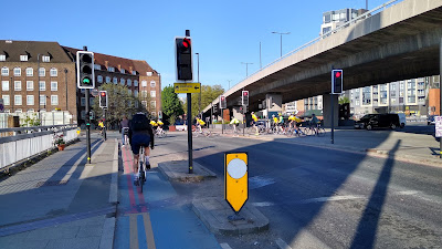 A cycle lane protected by a kerbed island to the right with traffic further right. There are separate signals for cycles and general traffic.