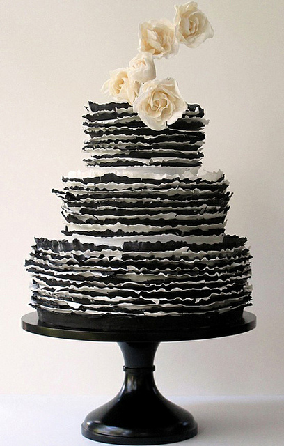 Set over three round tiers a black and white striped ruffle cake with cream