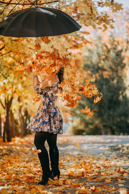 Mädchen_unter_Regenschirm_aus_dem_Herbstlaub_fällt