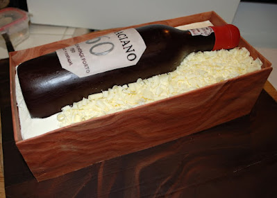 Adding chocolate shavings around sugar bottle on top of crate cake.