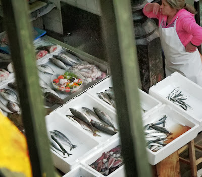 vendedor e banca com várias caixas de peixes expostos