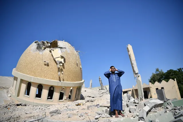 A Palestinian raises the call to prayer on the ruins of Al-Amin Muhammad Mosque, which was bombed by the occupation forces in Khan Yunis, Gaza, on October 20, 2023.
