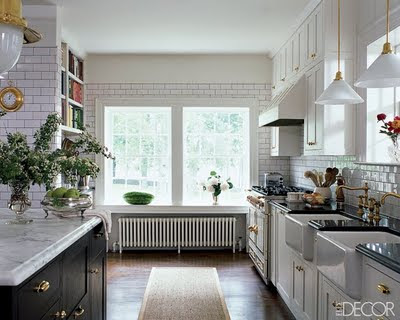  an island with black cabinetry and carrara marble countertops.