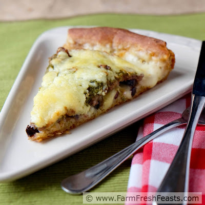 This pizza is layered with mozzarella cheese, marinated artichoke hearts, kalamata olives tucked under an Italian sausage blanket spread with garlic scape pesto.