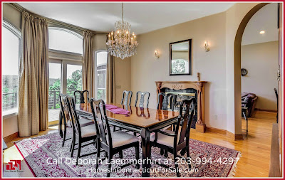 The elegant formal dining room in this waterfront home for sale in CT has walls of windows overlooking the pool and the breathtaking views.