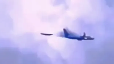 Silver metallic UFO appears behind airplane and accelerates away at speed.