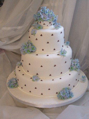 Four tier round wedding cake with pastel blue hydrangeas and pastel blue 