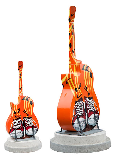 downtown Orillia outdoor art festival, large wooden painted guitars on display, this one is bright orange painted with red high-top sneakers with white shoelaces