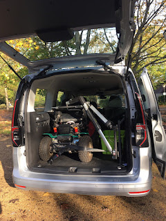 VW caddy with its boot open wide - and in the boot is an off road powerchair with a hoist attached. All tucked in nicely and the boot is so big the chair almost looks small!