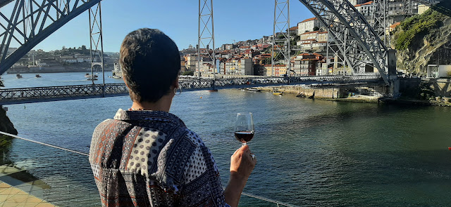 Mulher segurando copo de vinho do Porto a olhar para ponte Luis I, rio Douro e cidade do Porto