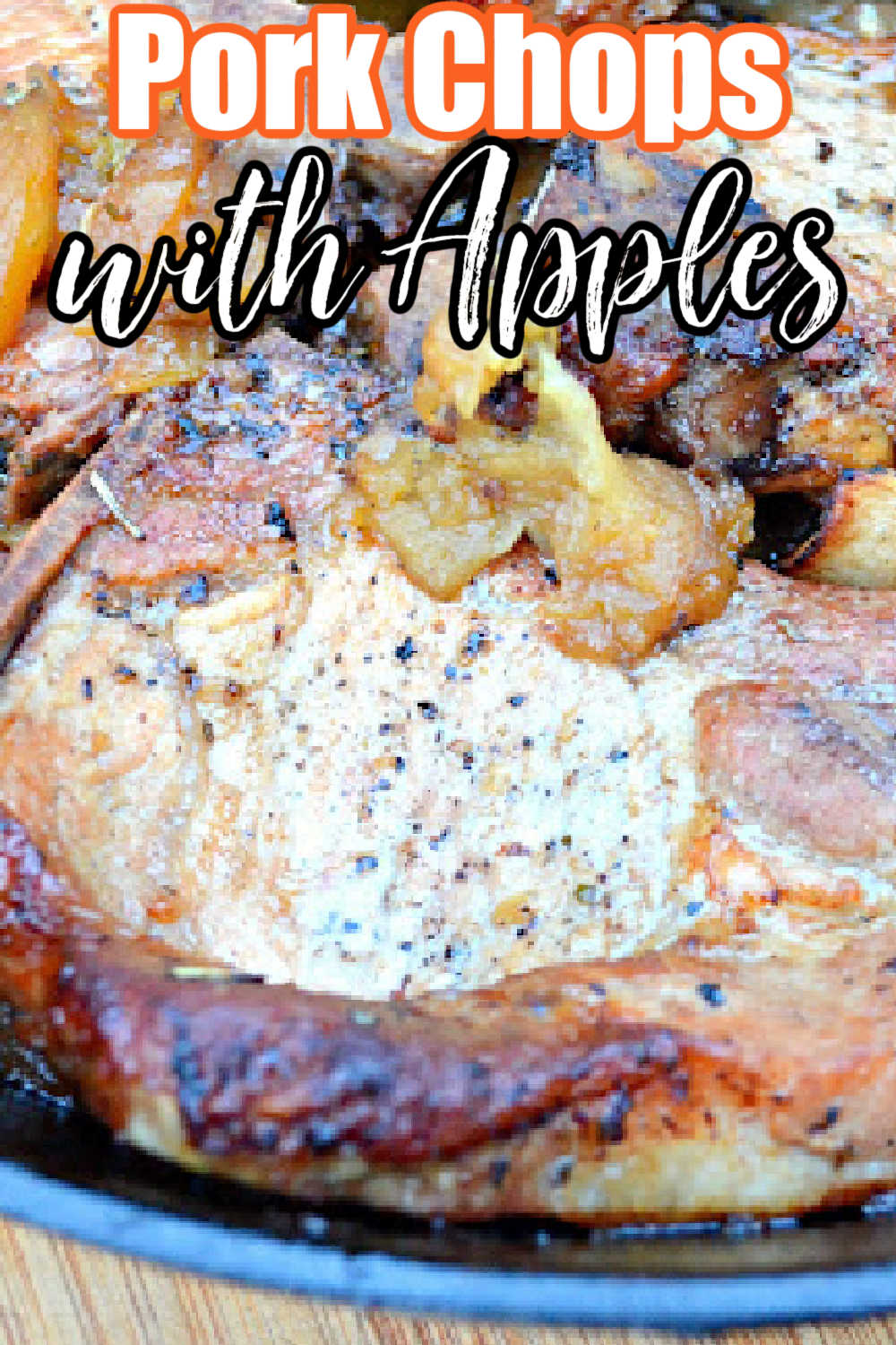 Pork Chops with Apples in a cast iron skillet on a wooden cutting board. White text with orange outline Pork Chops at the top and black text below it with apples.