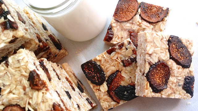 Honey, Walnut, and Fig Granola Bars sliced into squares and stacked next to a glass of milk