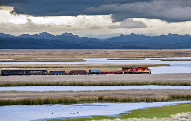 Train passes beside a beautiful landscape beside the Andes Mountain during the Southern Hemisphere summer. 